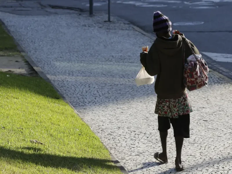 Indívíduo anda pela rua agasalhado por causa do frio